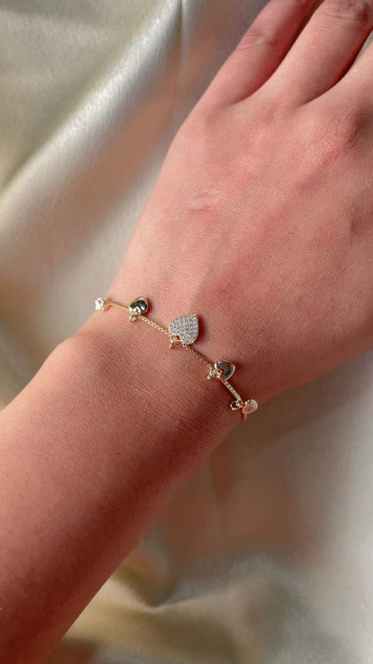Close-up of a hand wearing a delicate bracelet with small beads on a soft fabric background