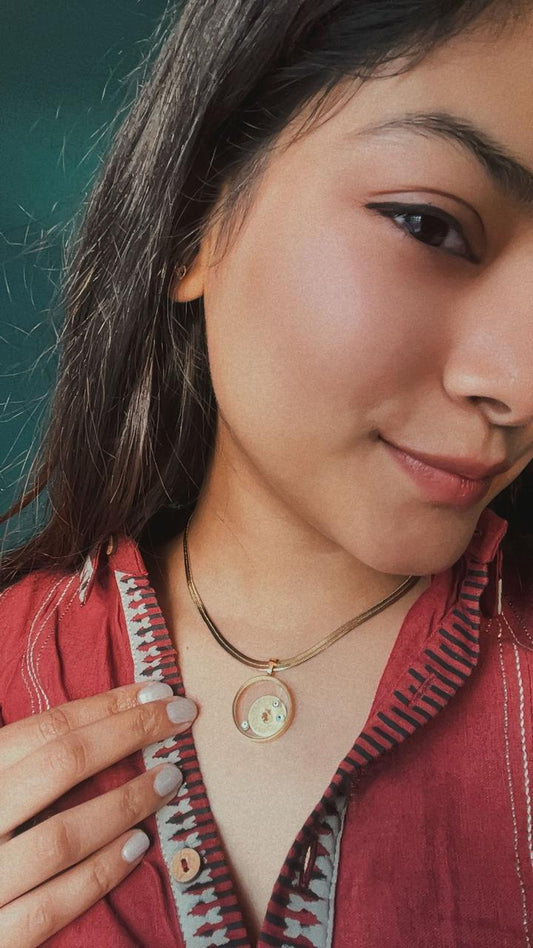 Woman wearing a red garment with a zipper and a necklace, against a teal background