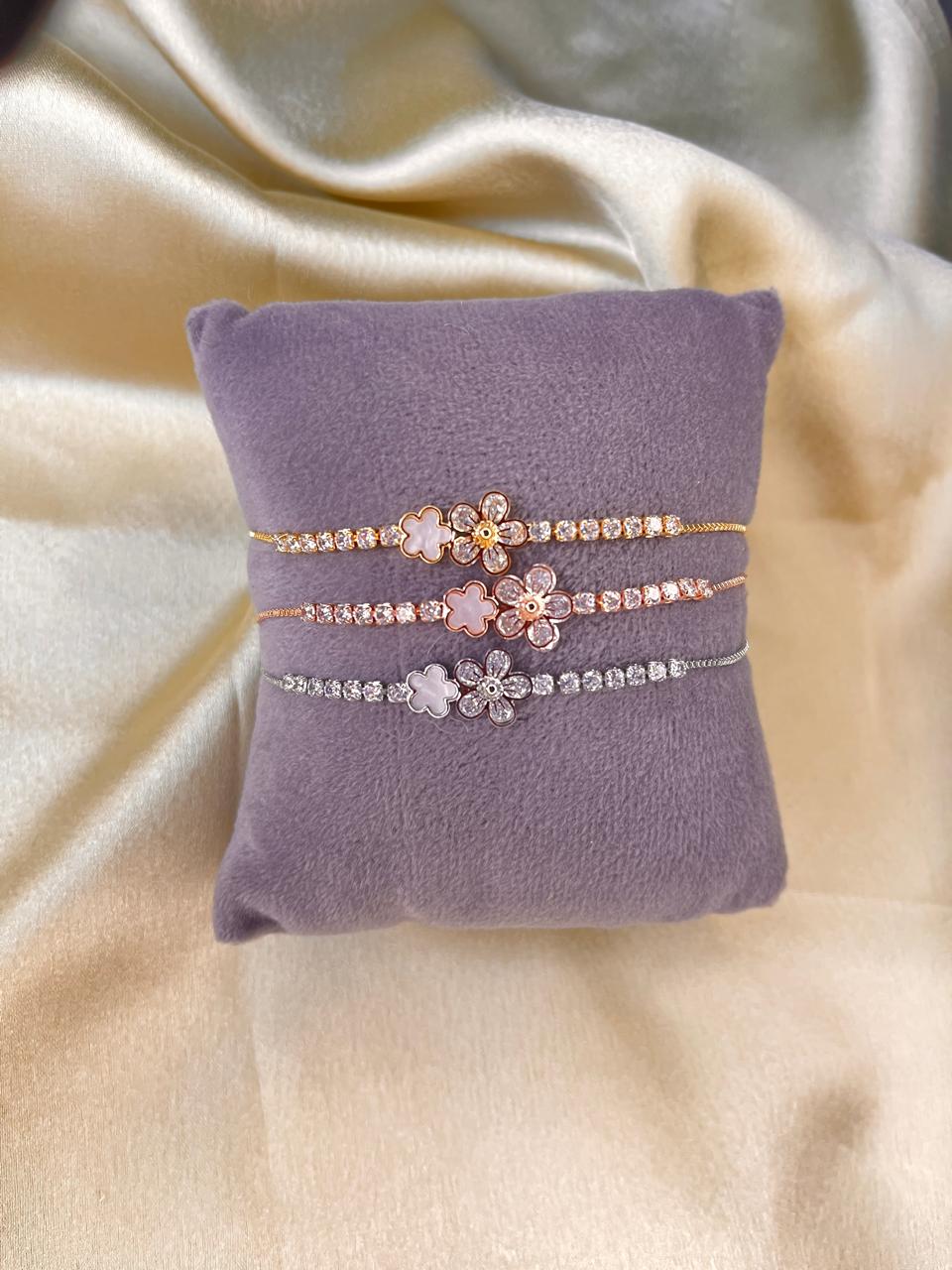 Two floral-patterned bracelets on a purple cushion with a beige fabric background