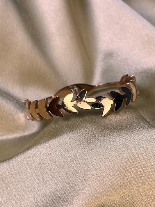 Gold bracelet with leaf design on a beige fabric background