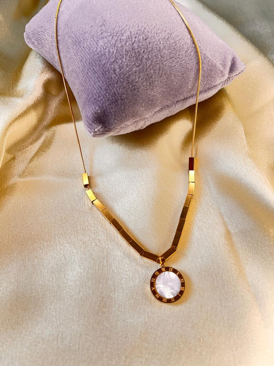 Gold necklace with a pendant on a beige surface