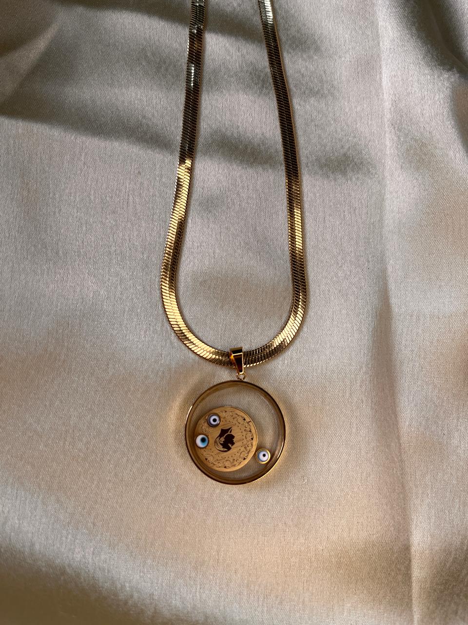 Gold necklace with a round pendant on a light fabric background
