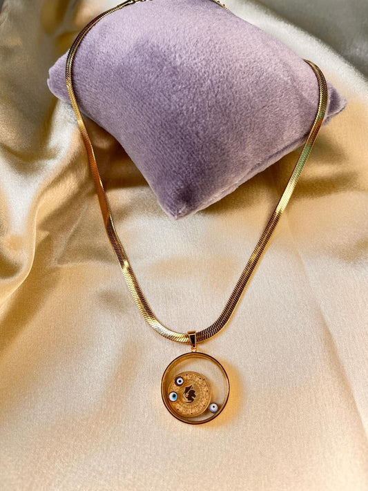 Gold necklace with a pendant on a beige fabric background