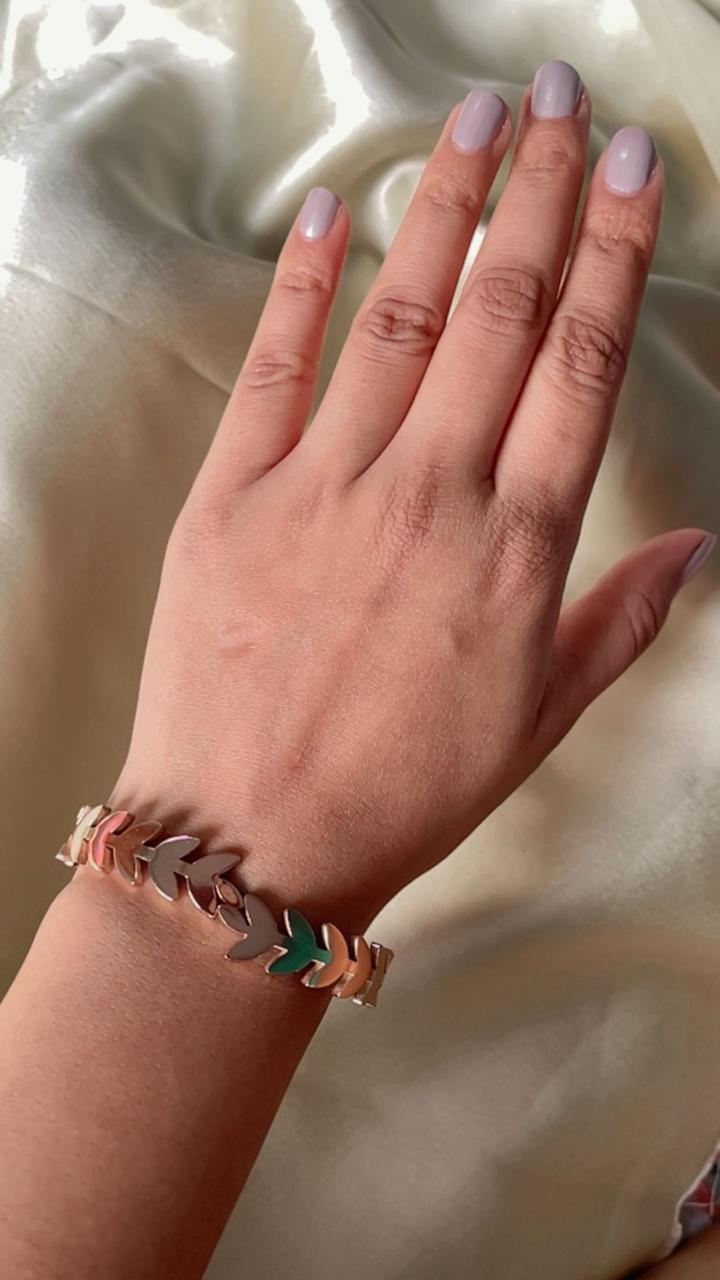 Hand wearing a bracelet with heart-shaped charms on a soft fabric background