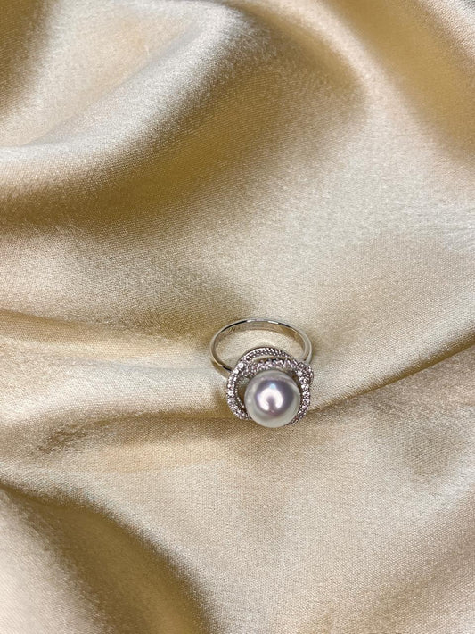 Pearl ring with silver band on beige satin fabric