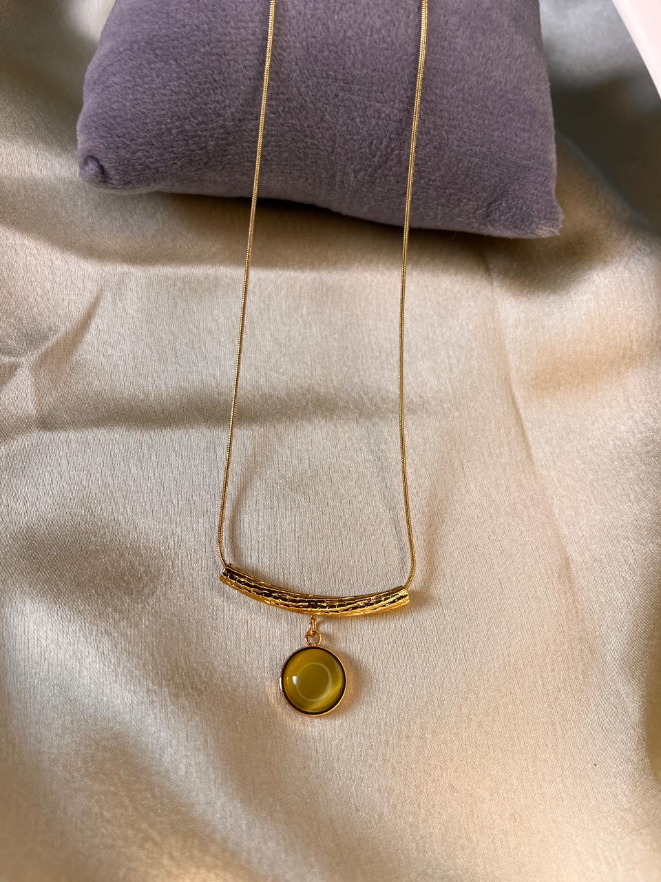Gold necklace with a round pendant on a beige fabric background